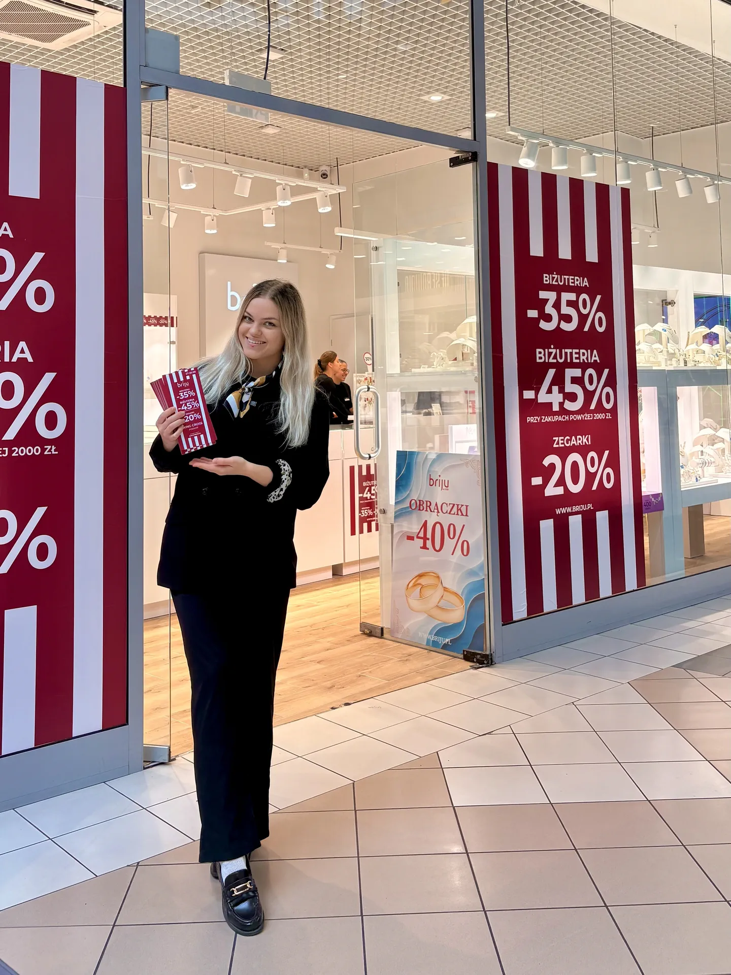 Hostessa agencji DNA z ulotkami promocyjnymi przed salonem Briju w galerii handlowej